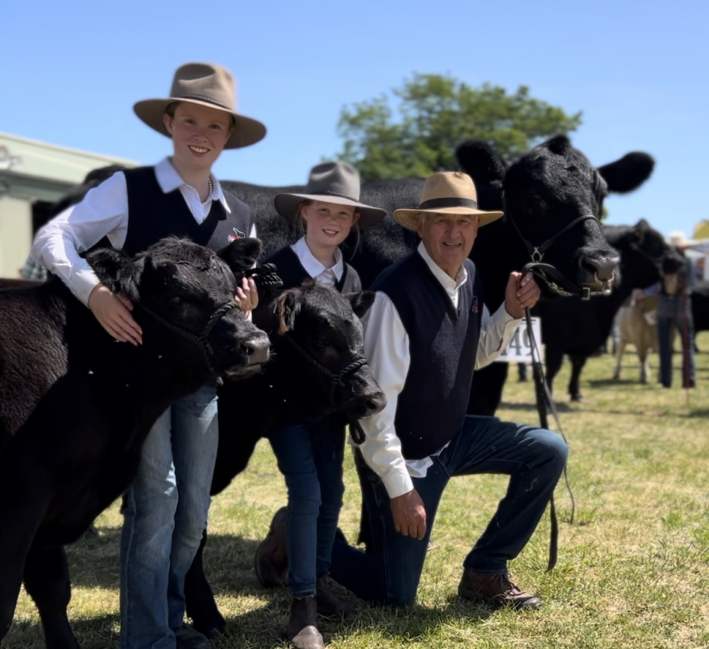 People posing with cows at an agricultural show.