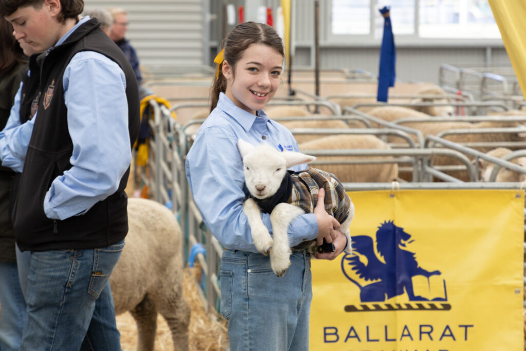 Smiling girl holding lamb at Ballarat farm show.
